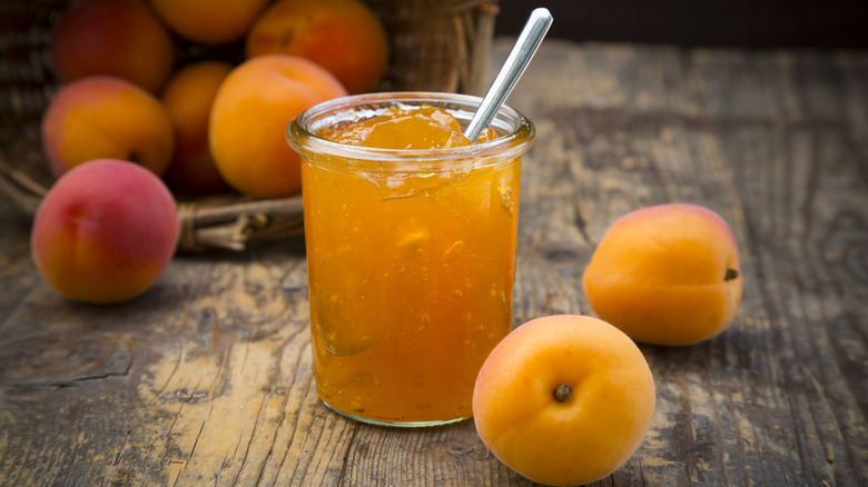 A jar of apricot jam with fresh apricots