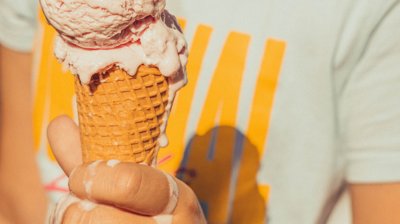 Hand holding a melting ice cream cone
