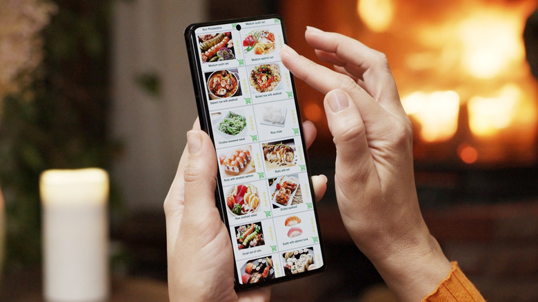 Someone scrolling through an online sushi menu on a smartphone