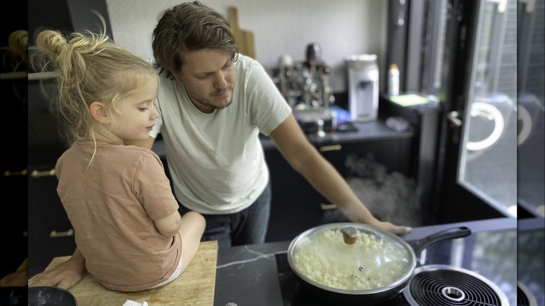 man and daughter watching popcorn pot