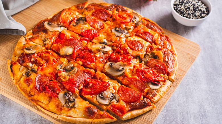 St. Louis style pizza with bacon, mushrooms and tomatoes on a board