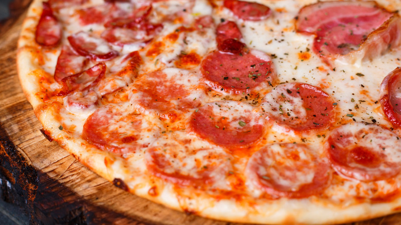 fresh pizza with bacon, salami, ham, pepperoni