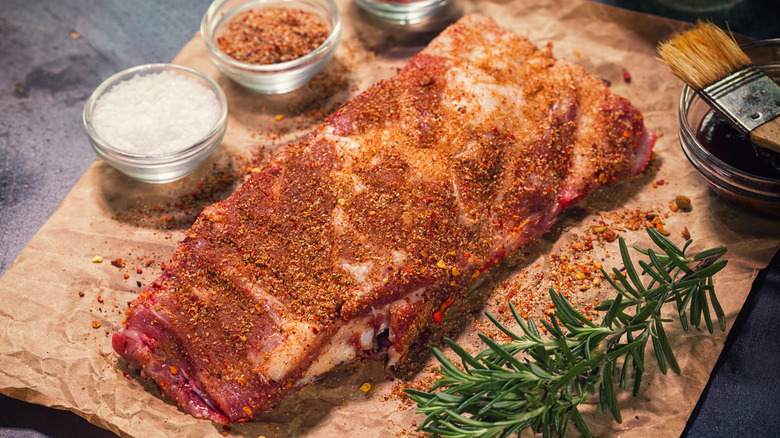 Spare ribs covered in a dry rub on a wooden board