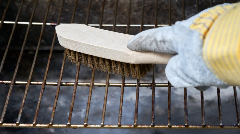 Usinf a wire brush to clean a BBQ grill plate