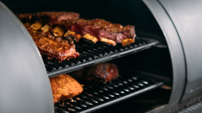 Closeup of poultry, beef and pork meat, ribs cooked in BBQ smoker.