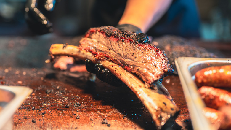 Closeup of someone holding smoked beef ribs