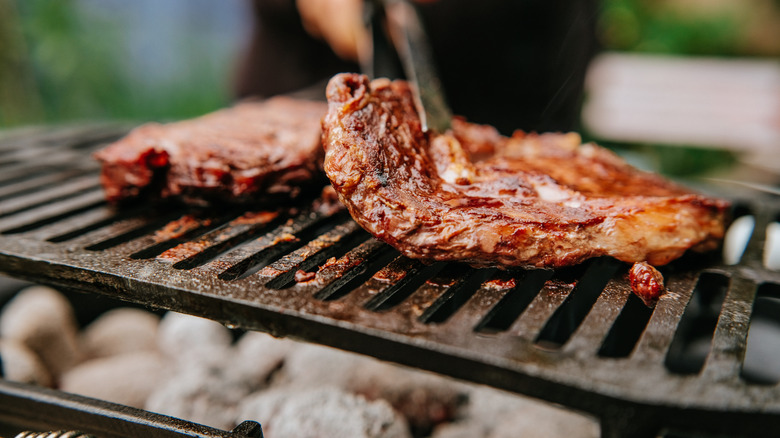 Woman doing BBQ steaks on a flame grill