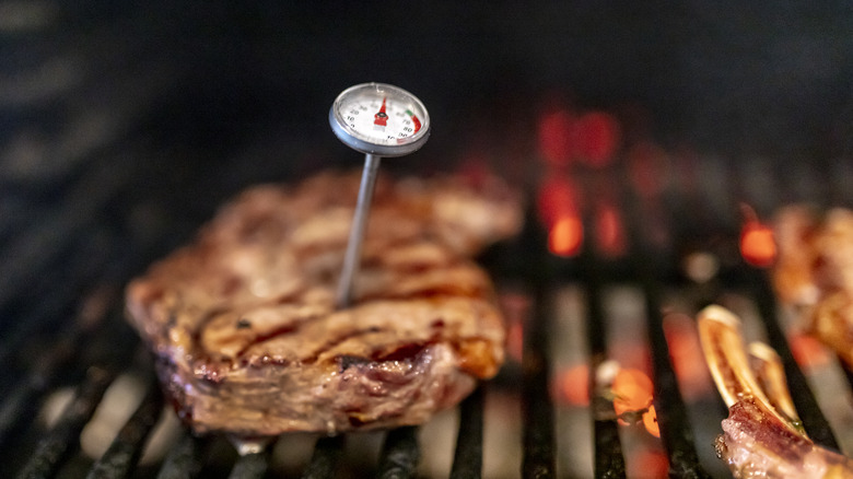 A meat thermometer in a steak on the barbecue