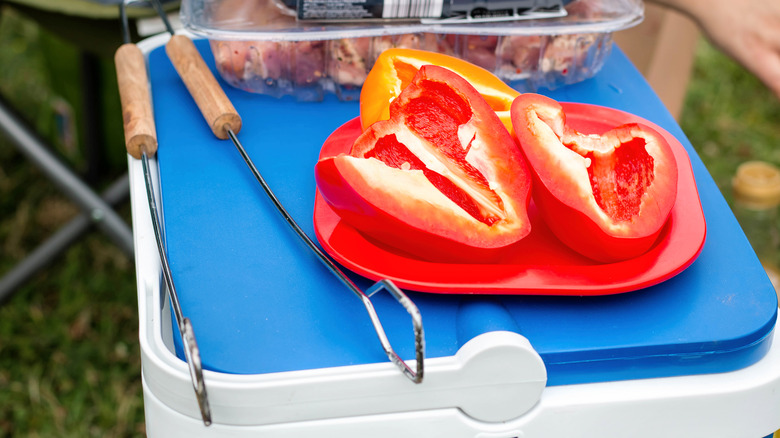 Close-up of a cool box with tongs and red peppers on top