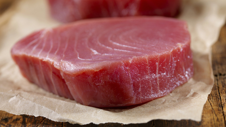Raw tuna steaks on parchment paper
