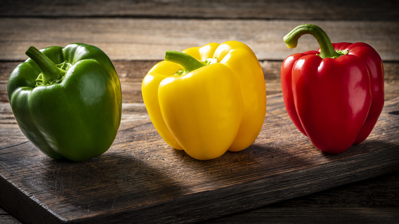 Three bell peppers on cutting board