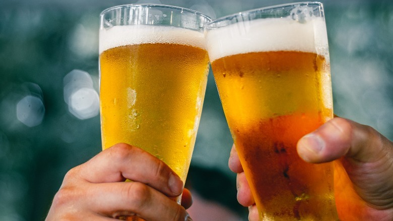 two hands clinking beer glasses