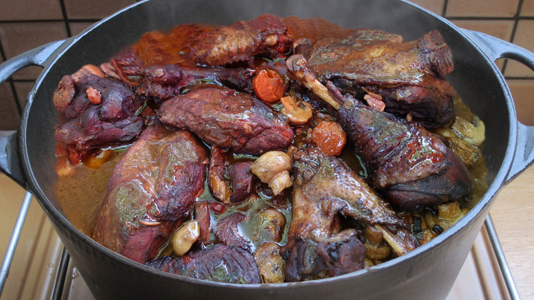 Coq au vin cooking in a cast iron casserole