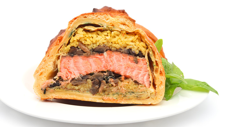 A sliced-open coulibiac on a white plate