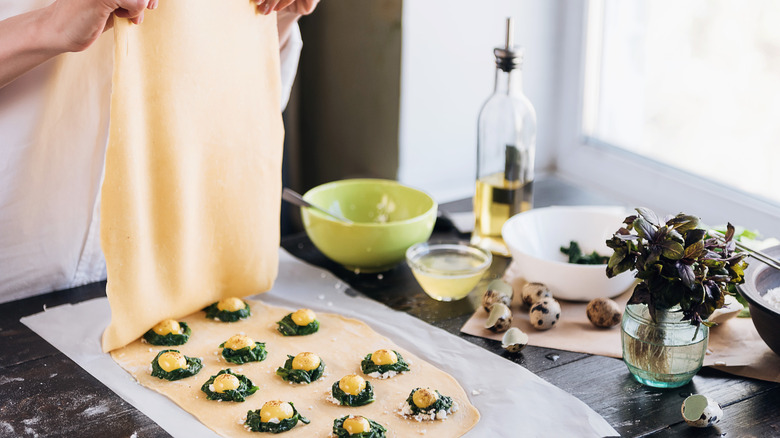 Chef preparing ravioli with quail eggs and spinach