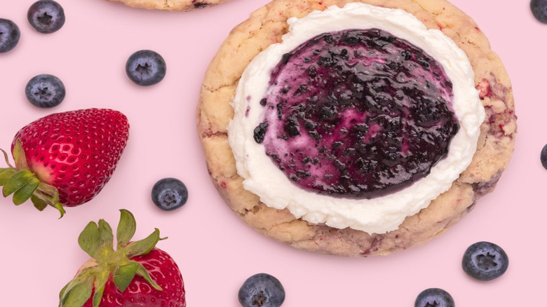 Overhead image of Crumbl's Berries and Cream cookies on pink background with scattered berries