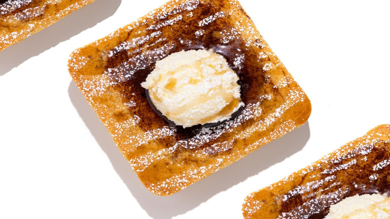 Overhead image of square-shaped Crumbl French Toast cookie with scoop of buttercream on white background