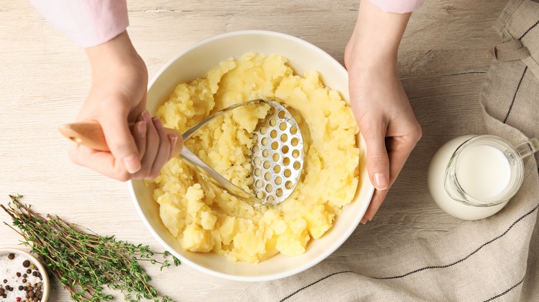 A person using a potato masher