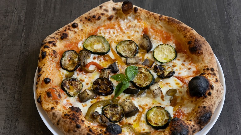 A pizza with cooked zucchini and mushrooms