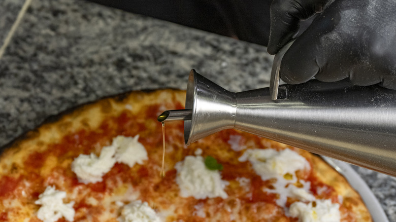 drizzling olive oil on pizza