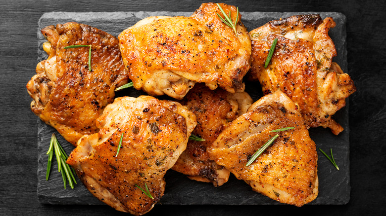 Golden chicken thighs on a black slate