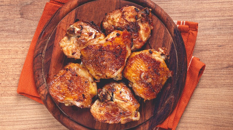 Fried chicken thighs on a round chopping board