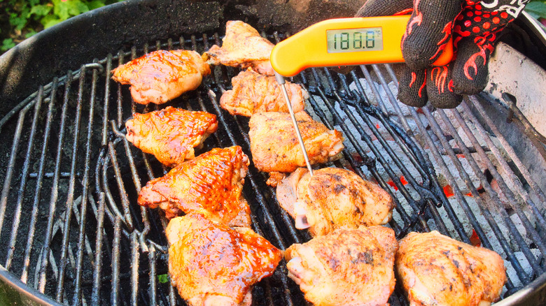 Checking the temperature of barbecued chicken thighs
