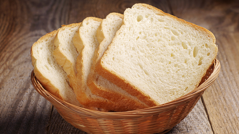 Toast bread in wicker basket on old wooden table