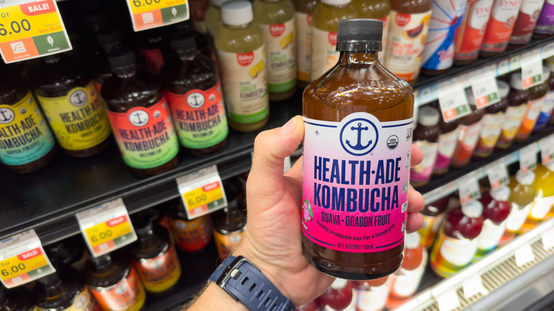 Someone holding a bottle of Kombucha in a store