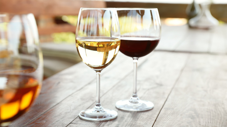 A glass of white and red wine on a wooden table