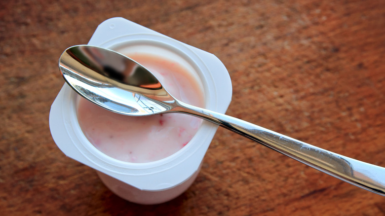 Pink yogurt in white plastic cup with spoon on it
