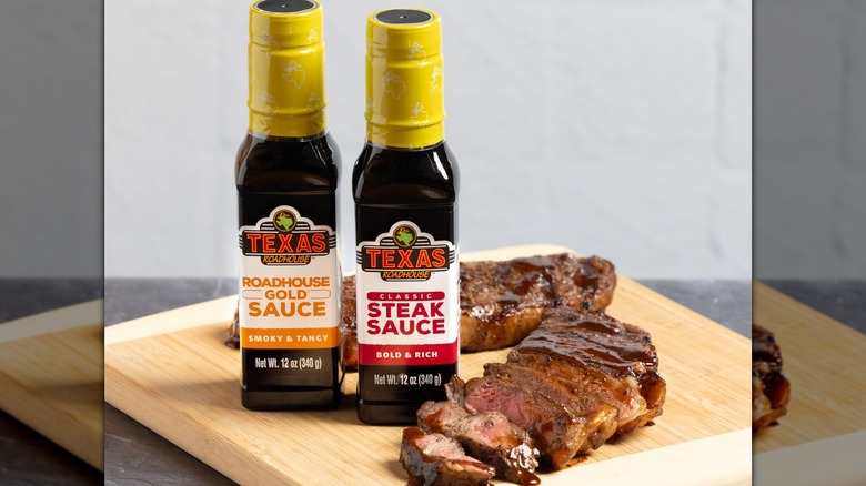 Two bottles of Texas Roadhouse sauce with a cut steak