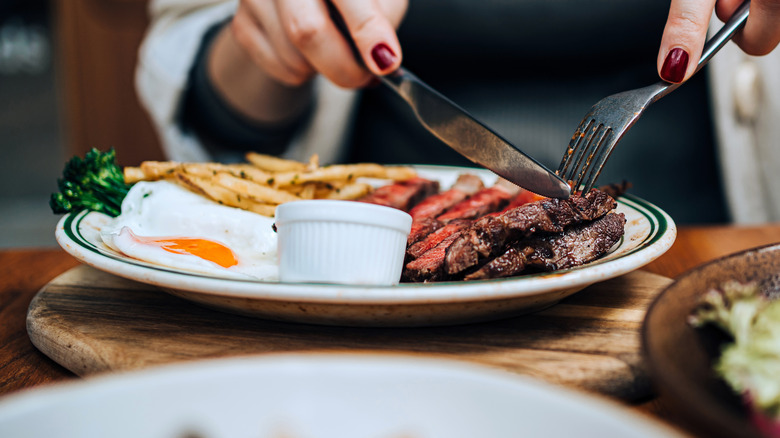 Someone cutting into a steak dinner
