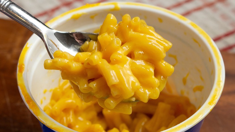 Spooning macaroni and cheese from a package cup
