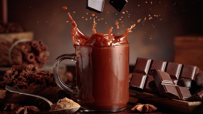 A glass of hot chocolate with squares of chocolate falling into it