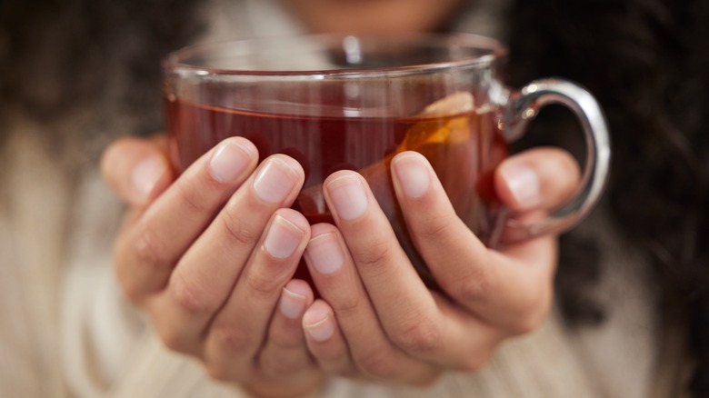 Someone holding a clear cup of tea