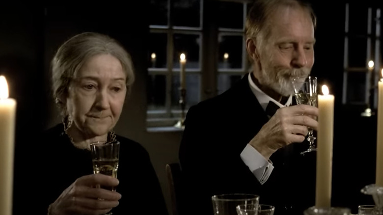 Two elderly people holding glasses of champagne at candlelit dinner