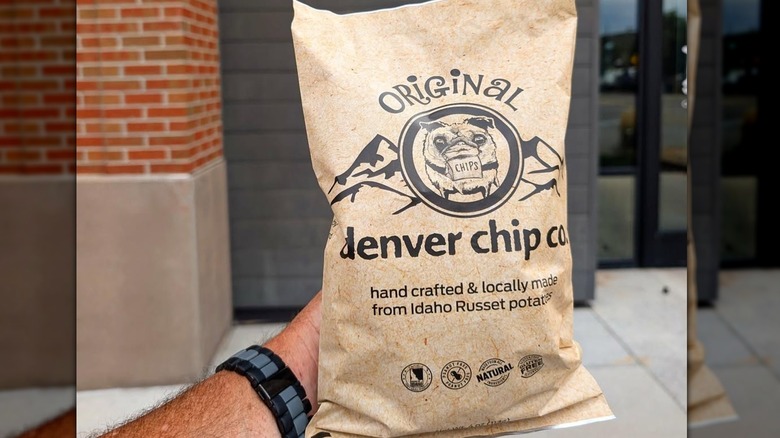 A hand holding a pack of Denver Chip Co. Original chips