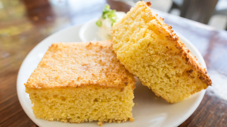 Two pieces of cornbread on a white plate