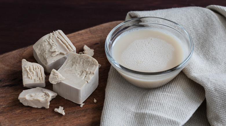 Live yeast on a wooden board and a cup with activated yeast