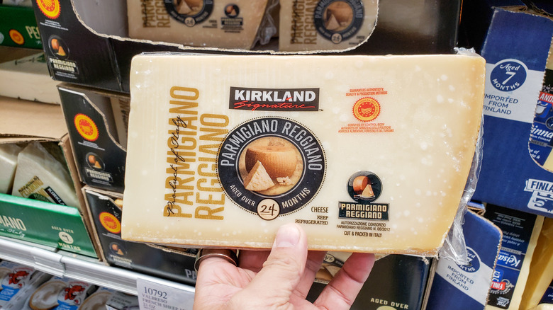 Someone holding a slice of Kirkland Signature Parmigiano Reggiano
