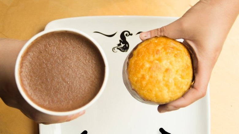 Hands holding a hot chocolate and cornbread