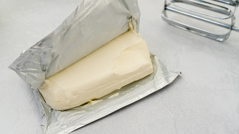 A partially opened block of cream cheese on a white surface