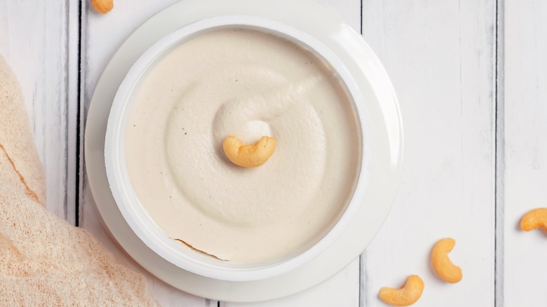 A bowl of cashew nut cream on a white table