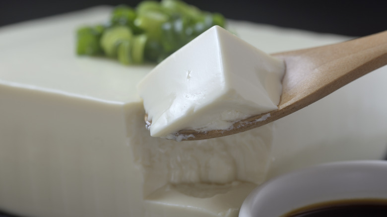 A block of silken tofu with a small spoonful removed