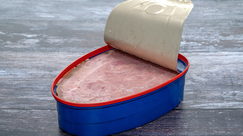 An open can of ham on a grey surface
