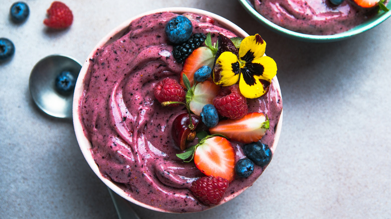 Two summer acai smoothie bowls with strawberries and blueberries