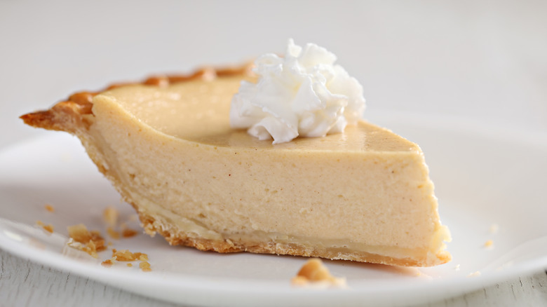 An extreme close up of a slice of chess pie with whipped cream