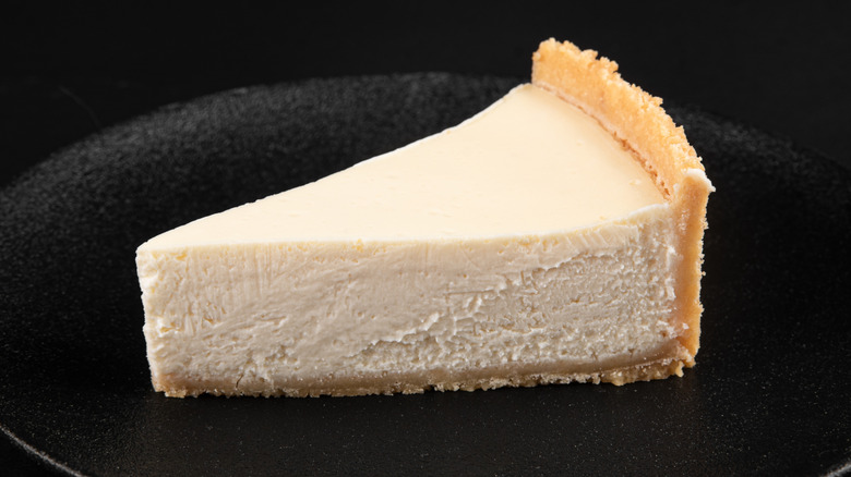 New York cheesecake on a dark plate on a black background