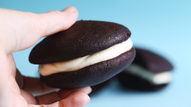 Someone holding a whoopie pie against a blue background